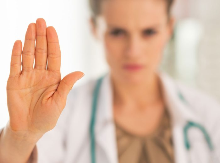 Ärztin hebt Hand zu Stoppzeichen, symbolisiert Medical Gaslighting